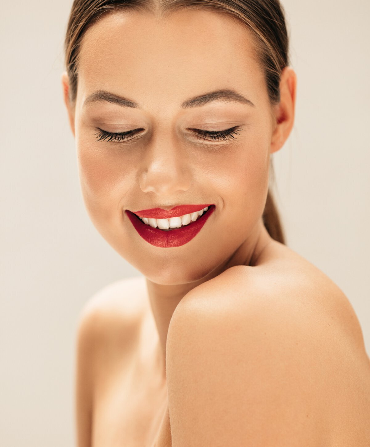 Manchester Lip Fillers model with looking down and smiling with red lipstick on